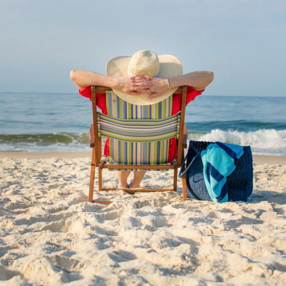 Lady with a sun hat relaxing in a beach chair near the shore