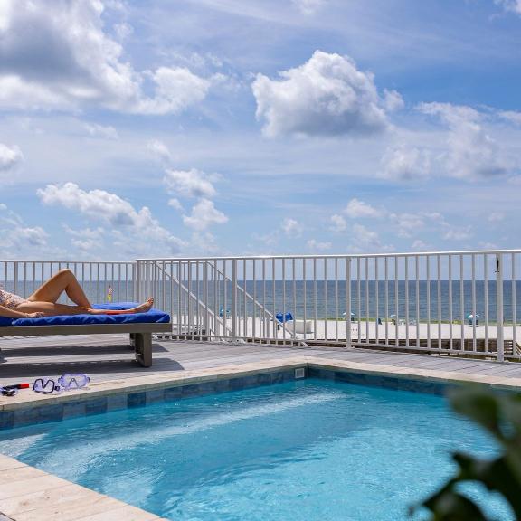 Woman lounging by a private pool at her beachfront vacation rental